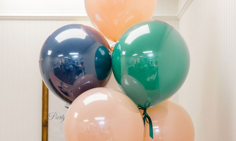 Blush, navy and green balloons tied to a Party Properly tote
