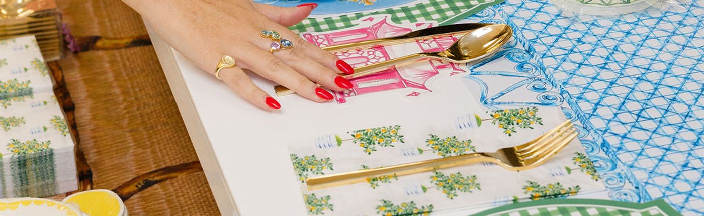 Overhead of a long table set with gingham, gold cutlery and layered plates