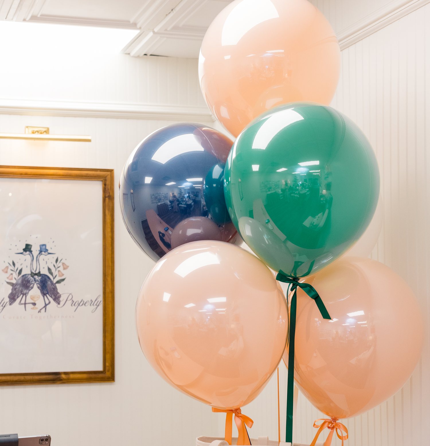 Balloon arrangement in navy, blush and green on a branded tote